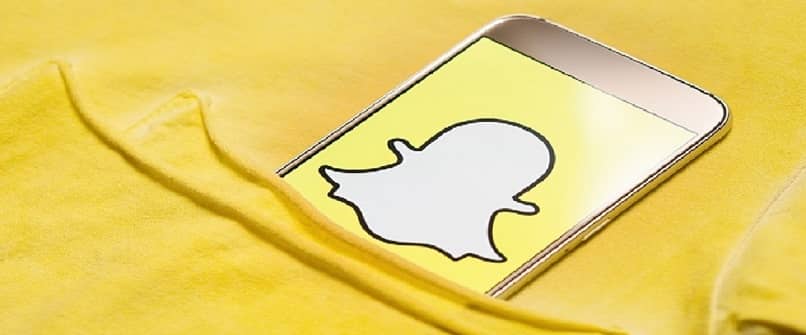 yellow background highlights a cell phone with the snapchat logo from a pocket