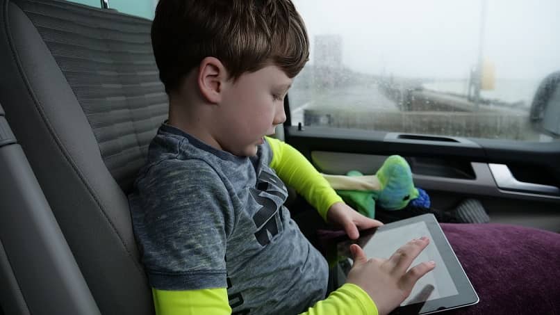 niño sentado en un carro usando una tablet