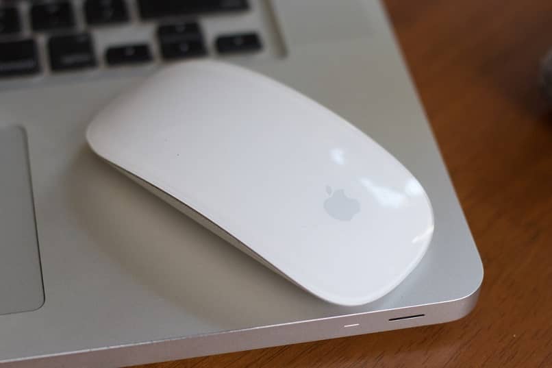ratón reposando encima del teclado de la laptop configurado para invertir la dirección del desplazamiento