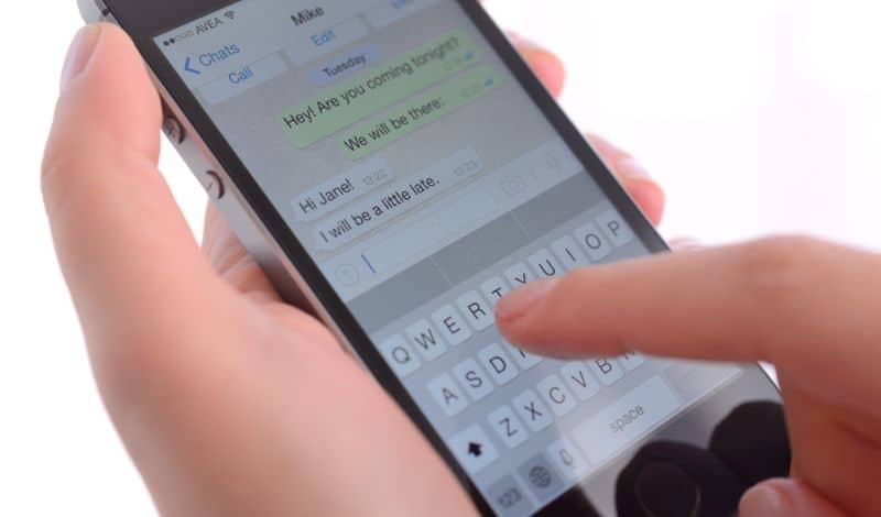 iPhone en mano enviando Mensajes de WhatsApp