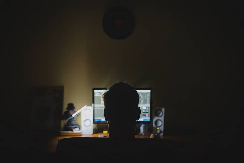 hombre observa la luz del monitor en una habitacion oscura