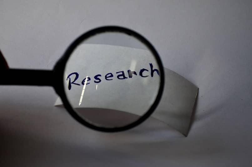 piece of paper with the word research seen through a magnifying glass 