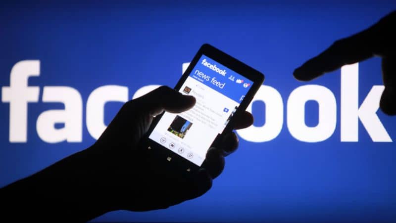 Facebook, hombre con celular en la mano