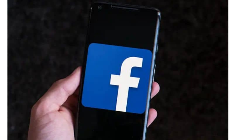 Logo Facebook, celular en la mano