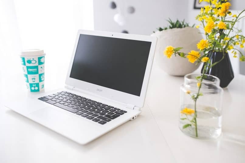 laptop en un escritorio y flores