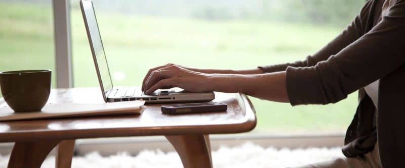 persona manejando laptop en una mesa con cafe y movil