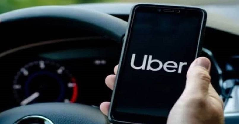 steering wheel with the hand on holding a mobile with uber